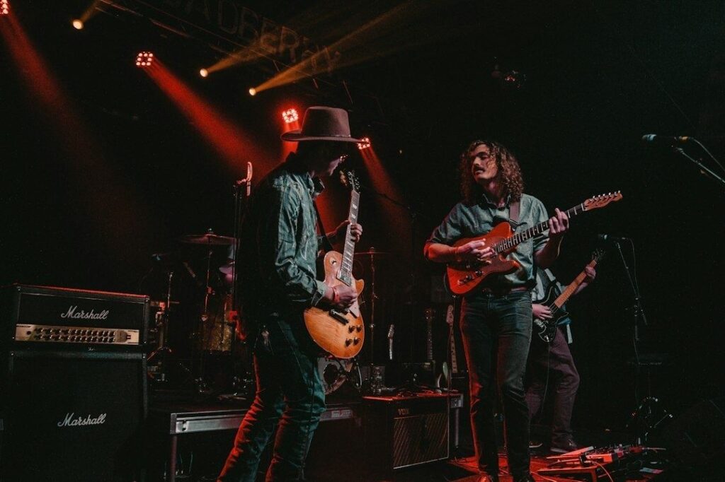 Bluesband spielt unter rotem Bühnenlicht mit Gitarren und Schlagzeug