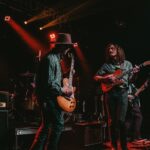 Bluesband spielt unter rotem Bühnenlicht mit Gitarren und Schlagzeug