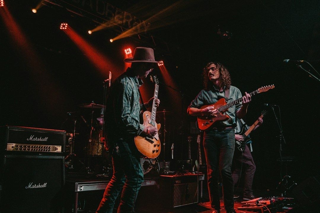 Bluesband spielt unter rotem Bühnenlicht mit Gitarren und Schlagzeug