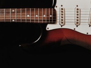 Nahaufnahme einer E-Gitarre mit Saiten, Griffbrett und Tonabnehmern
